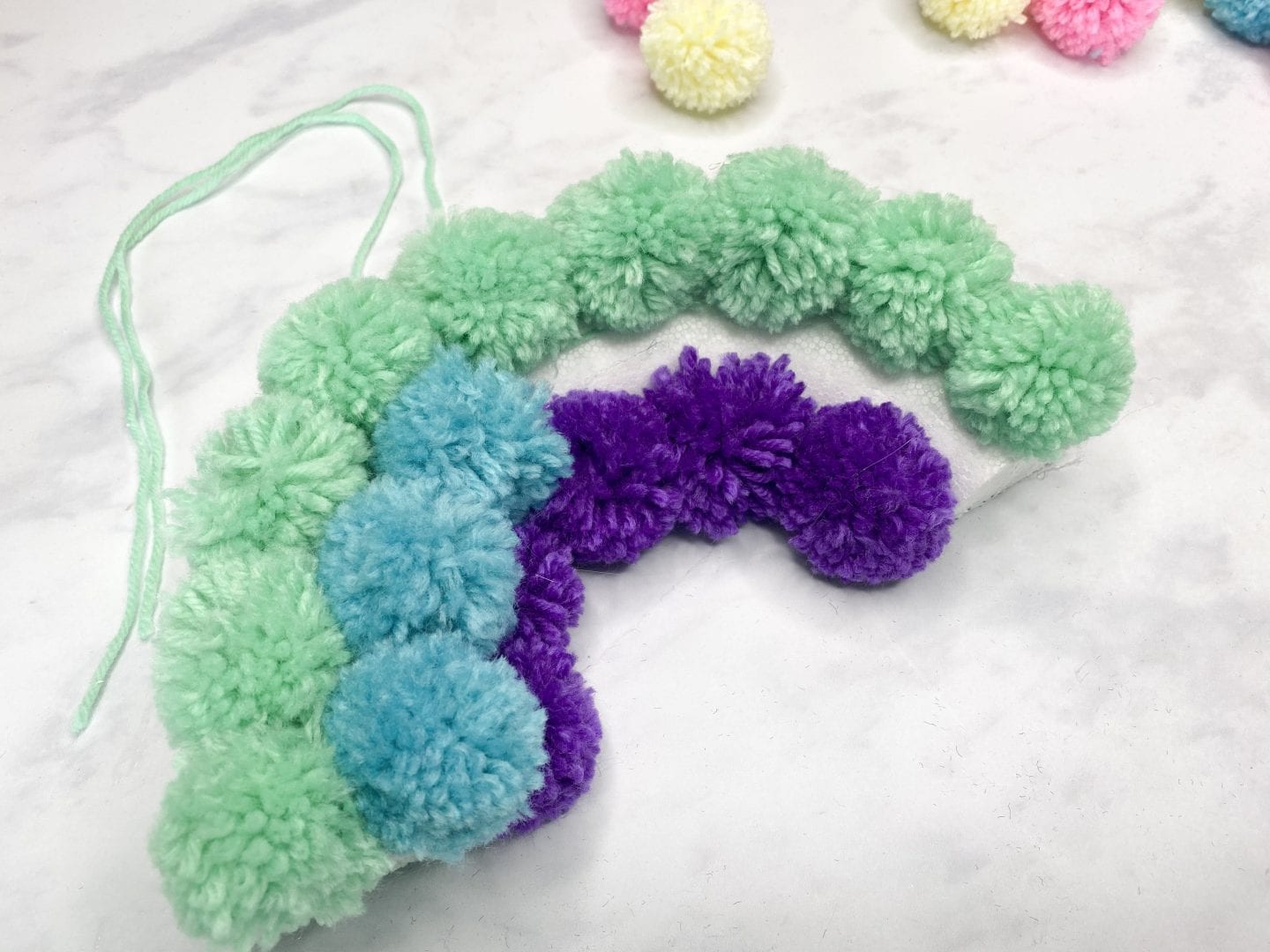 sticking the coloured pom poms onto the polysterene semi circle
