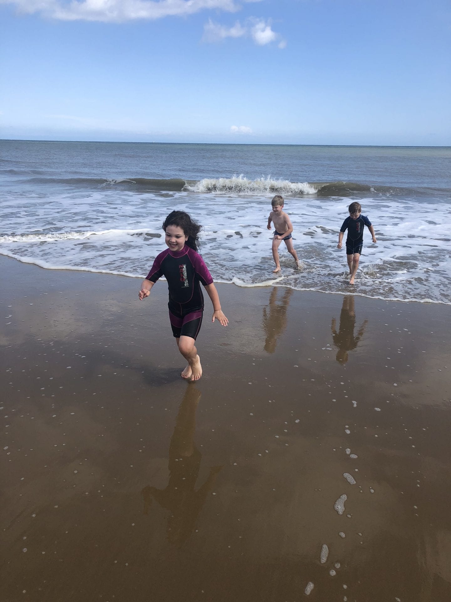 3 young children running away from the waves