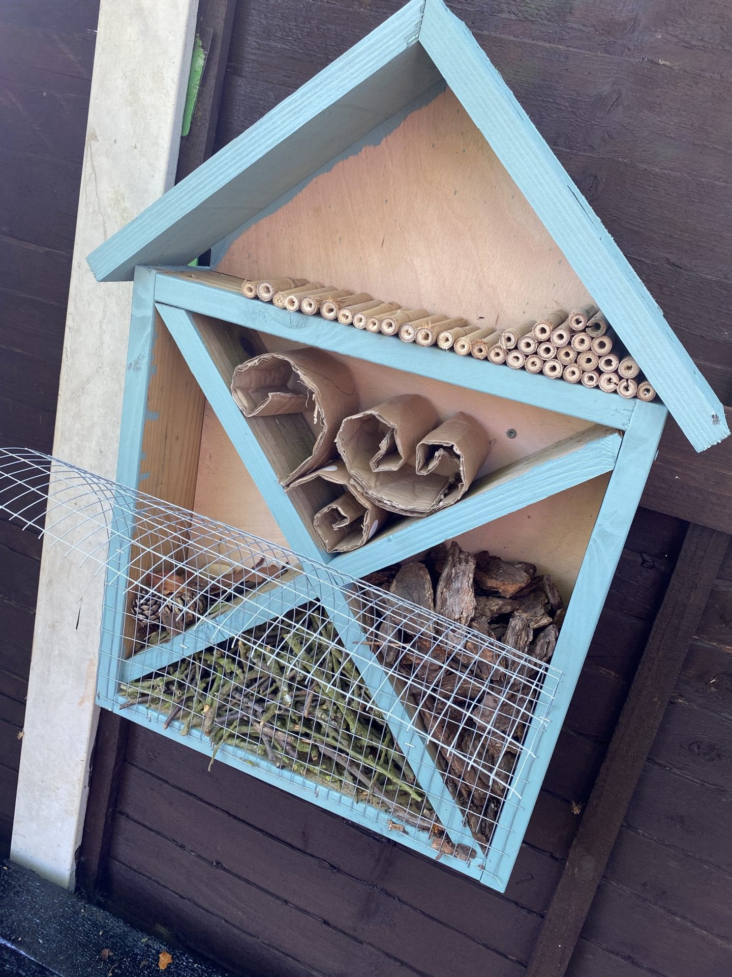 Filling up the bug hotel with hollow tubes, bark, sticks, cardboard and dry leaves and pine cones.