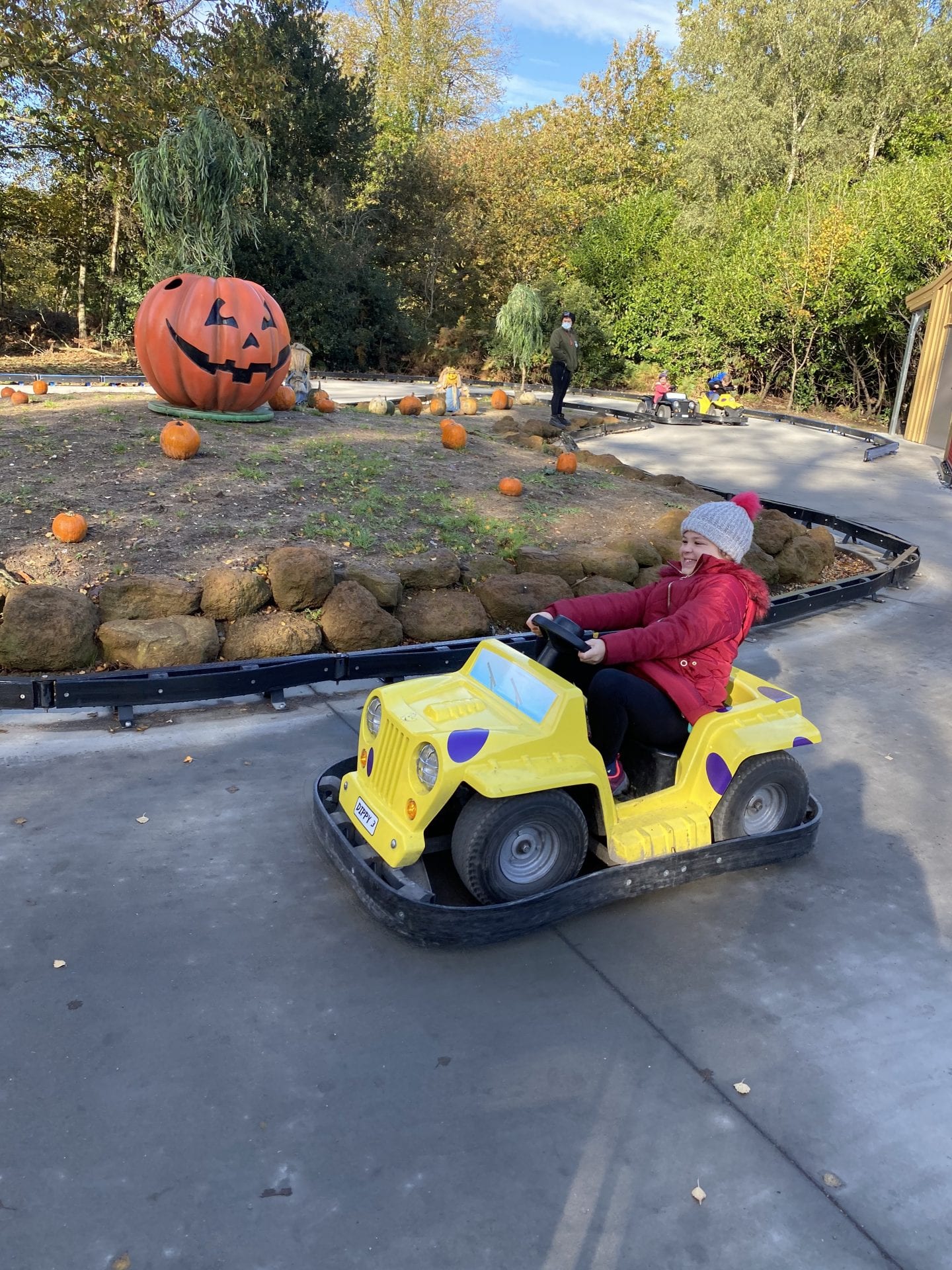 A young girl riding a yellow electric car around a small track.