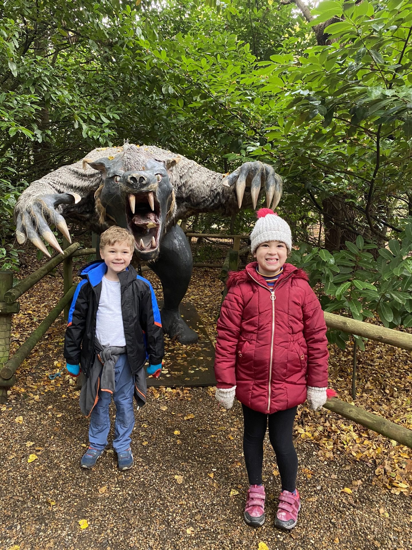 2 children standing in from of a statue of a werewolf
