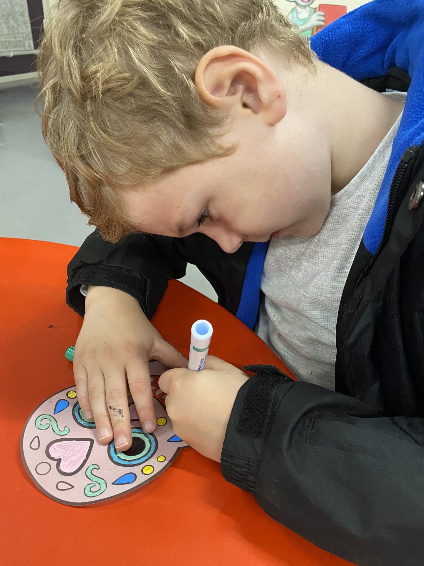 A young boy colouring in a sugar skull