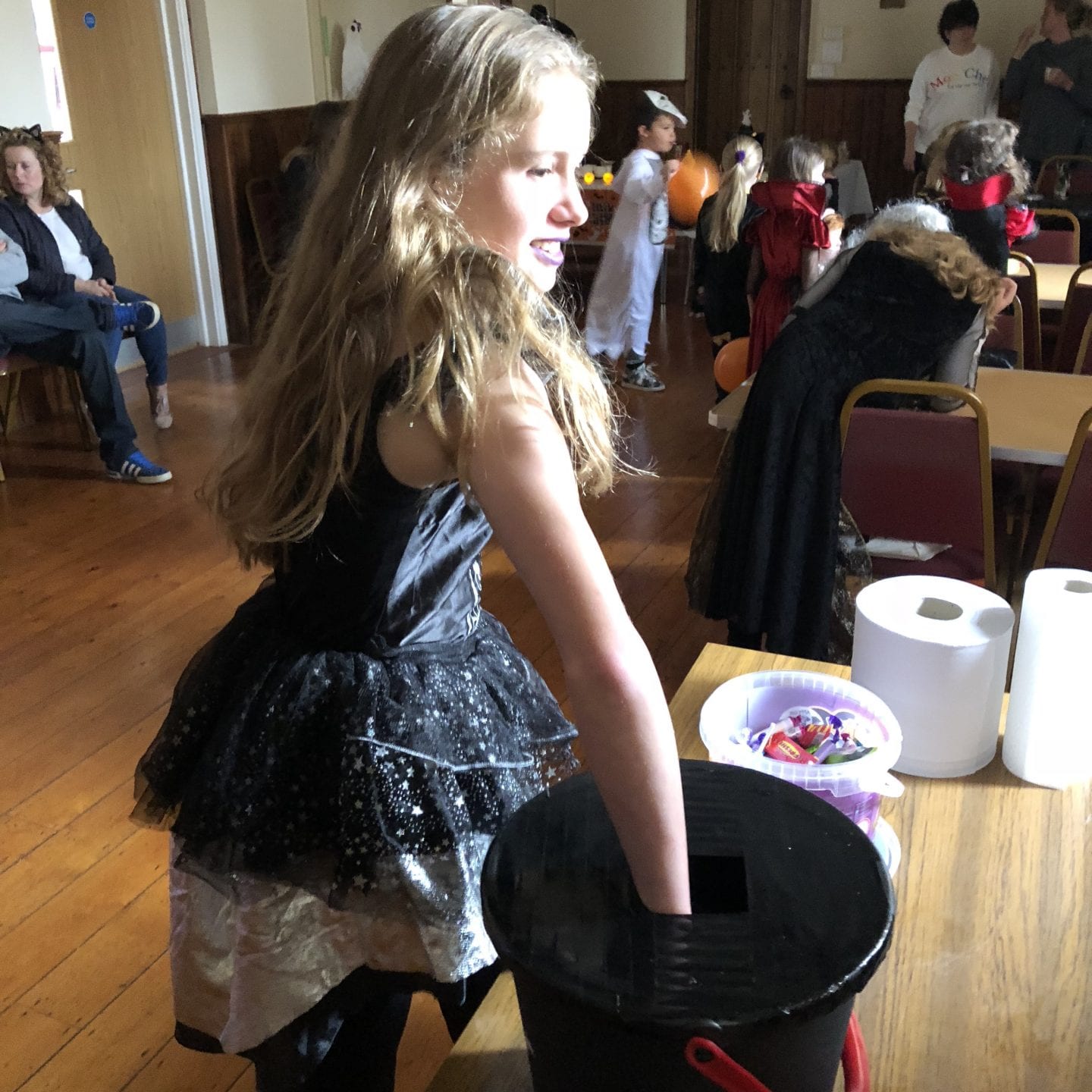 A young girl with her hand in a bucket of slime