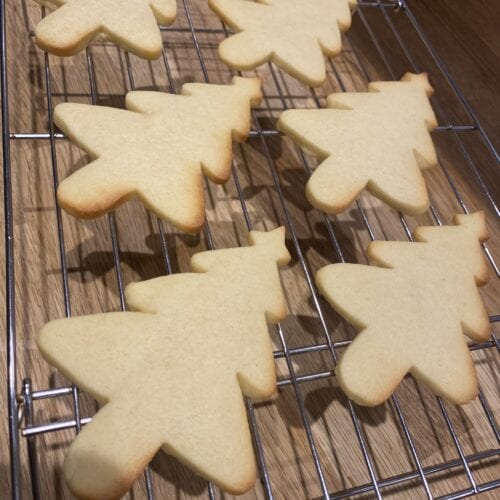 Christmas tree shaped sugar cookies on a cooling rack before icing