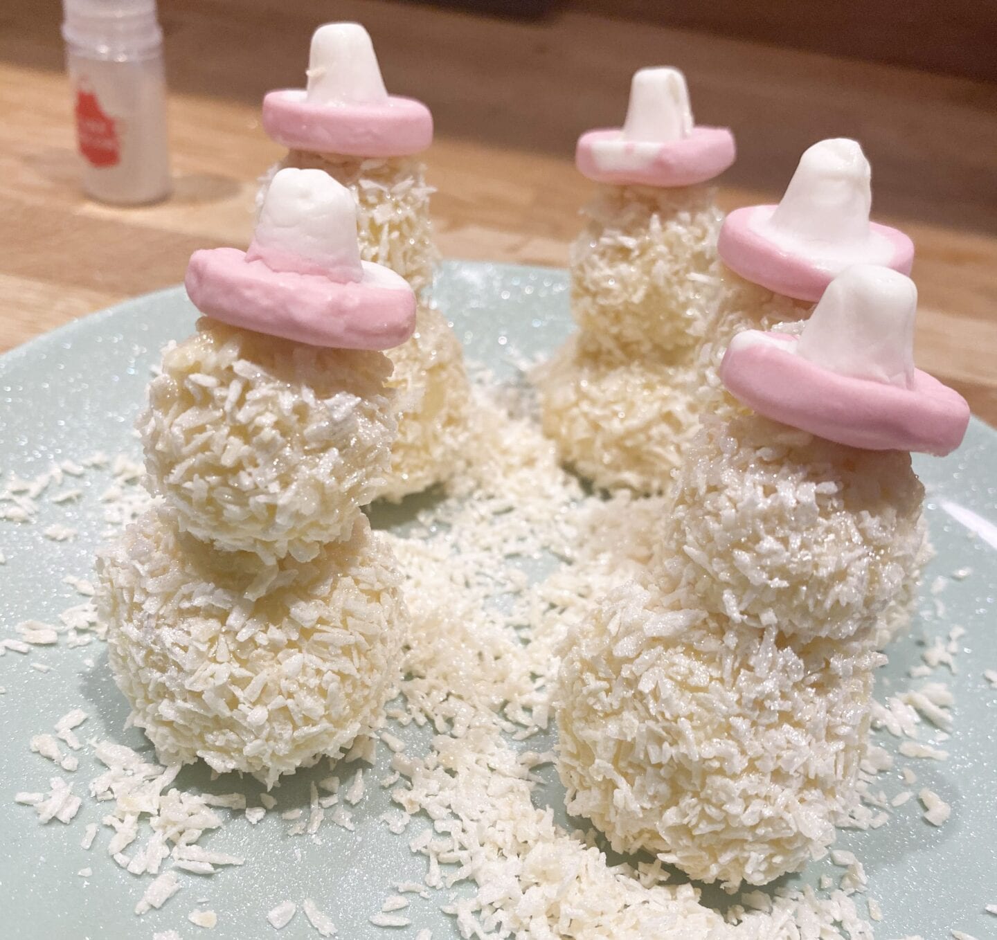 the start of the snowman truffles- two truffles coated in coconut on top of one another, with a raspberry mushroom hat.