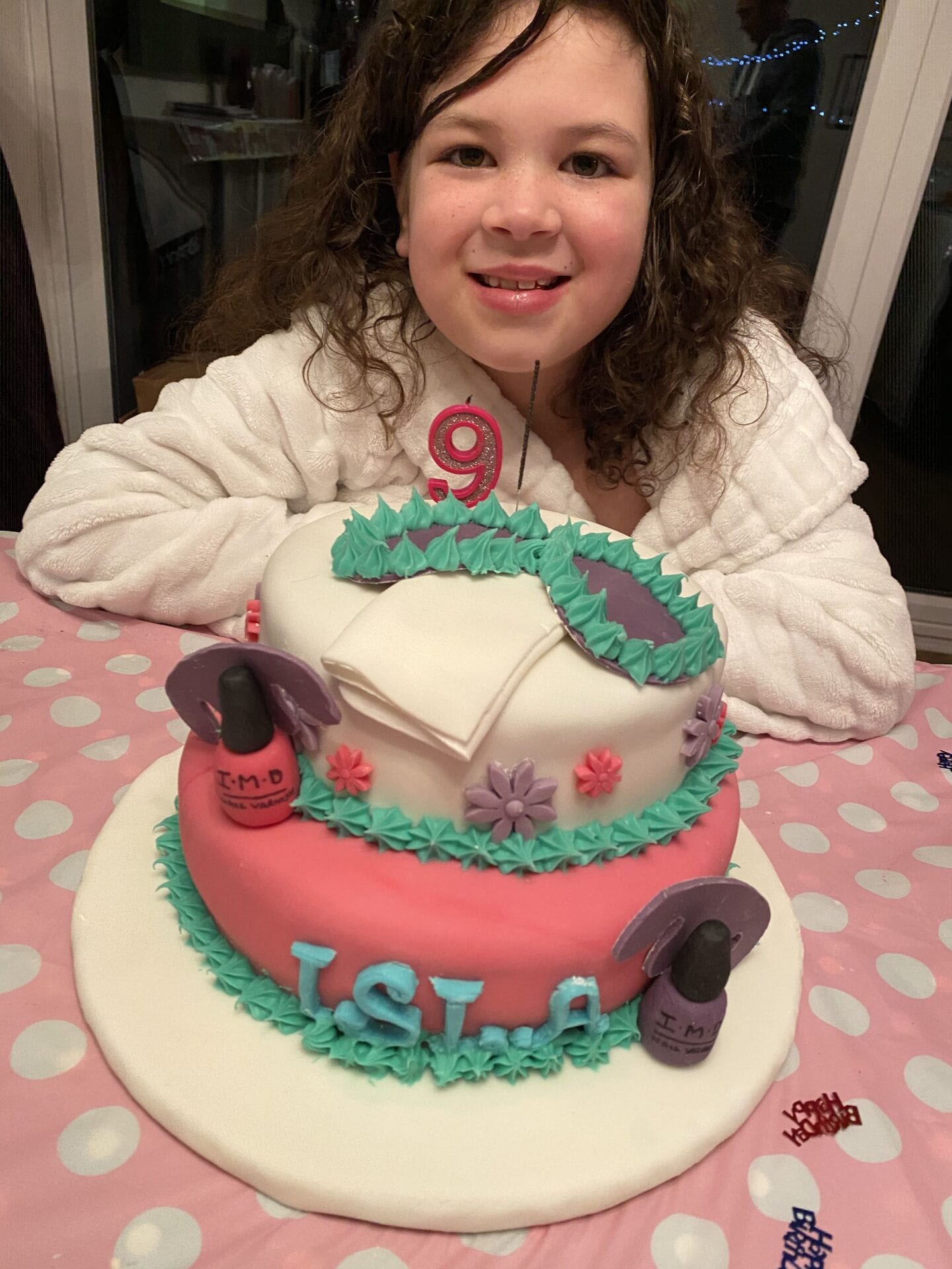 A young girl sitting behind her 'at home spa' themed birthday cake